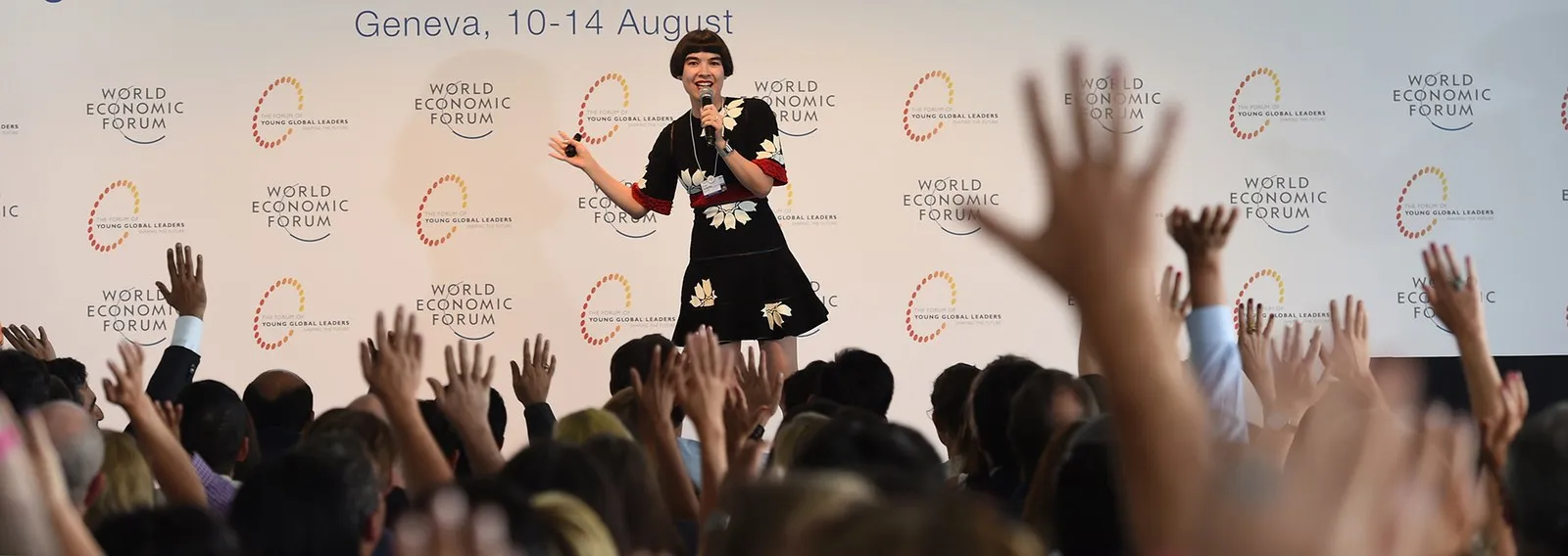 Drue Kataoka speaking at the World Economic Forum, Geneva — audience hands raised
